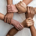 A birds eye view of 6 people, varying races interlinking hands, visualising unity.