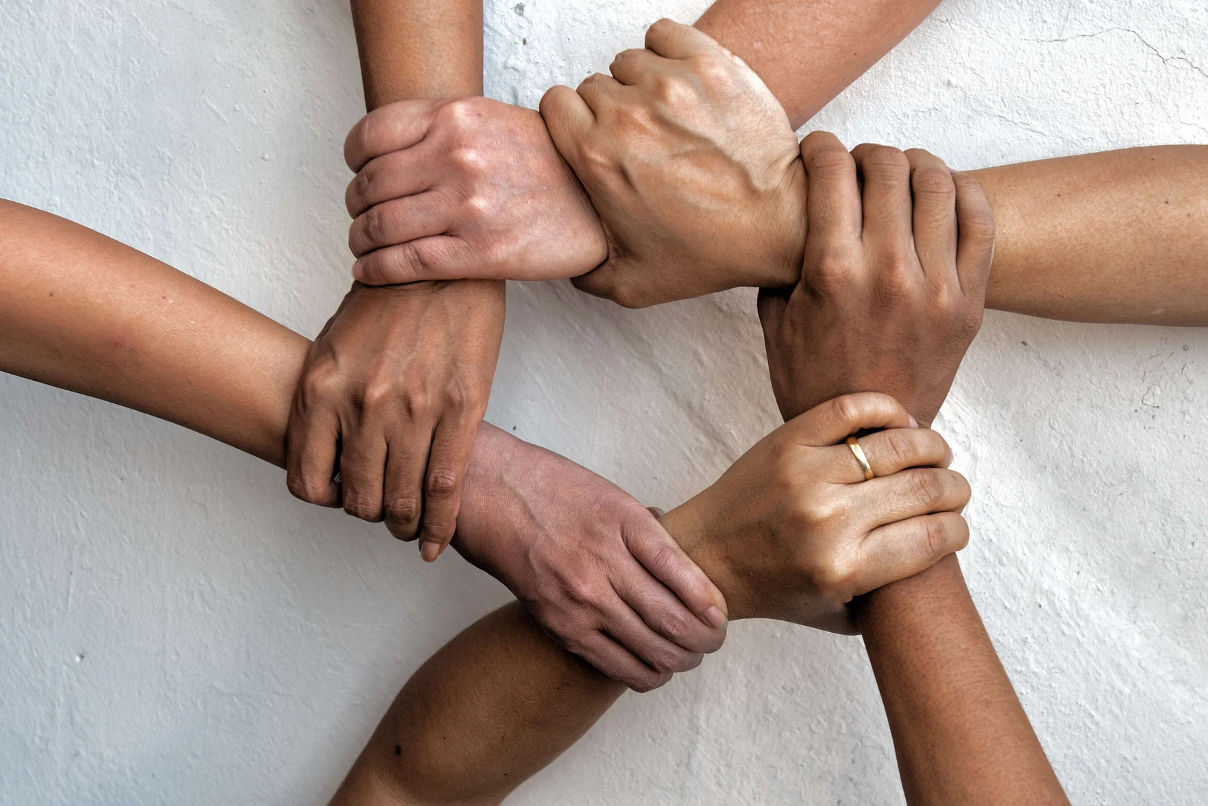 A birds eye view of 6 people, varying races interlinking hands, visualising unity.